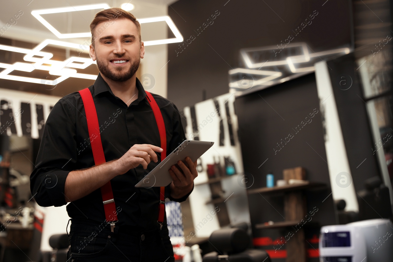 Photo of Young business owner with tablet in barber shop