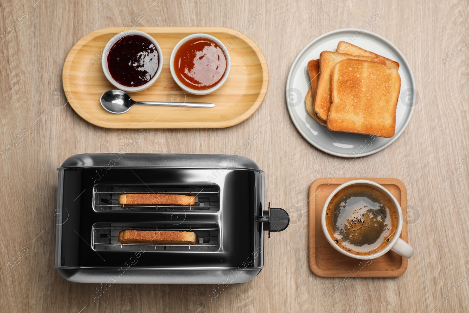 Photo of Toaster, roasted bread, jams and coffee on wooden table, flat lay