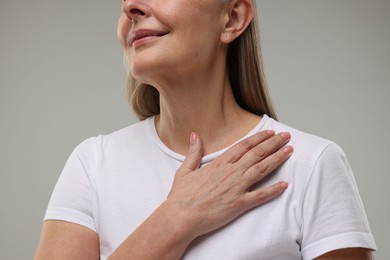 Mature woman with healthy skin on grey background, closeup