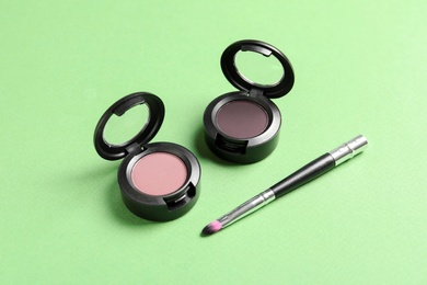 Photo of Eye shadows and brush on color background. Decorative cosmetics