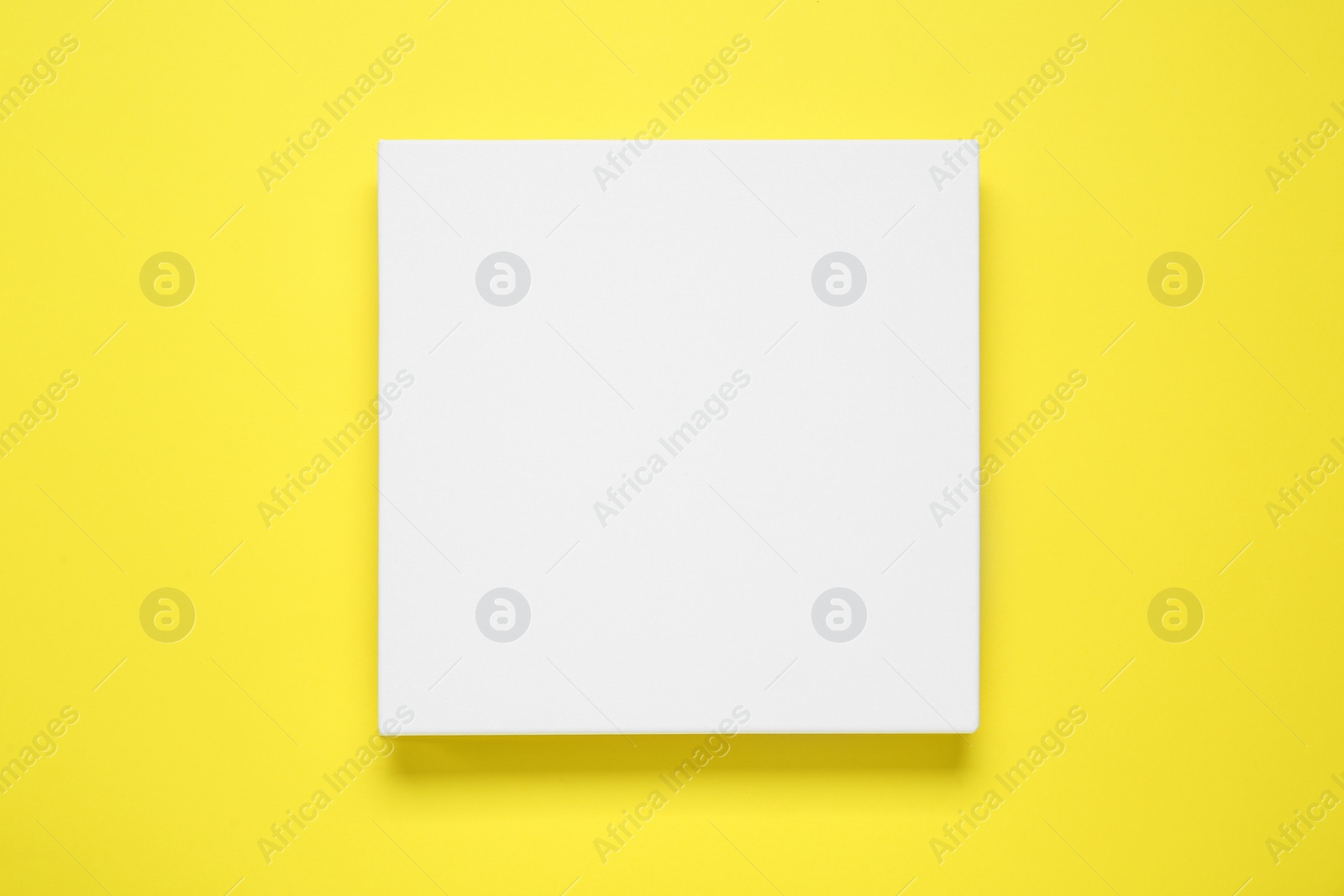 Photo of Blank canvas on yellow background, top view. Space for design