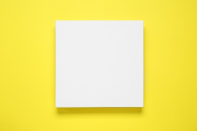 Photo of Blank canvas on yellow background, top view. Space for design