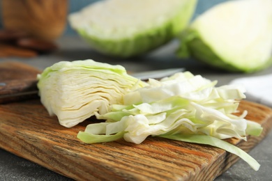 Photo of Cutting board with chopped and sliced cabbage on table