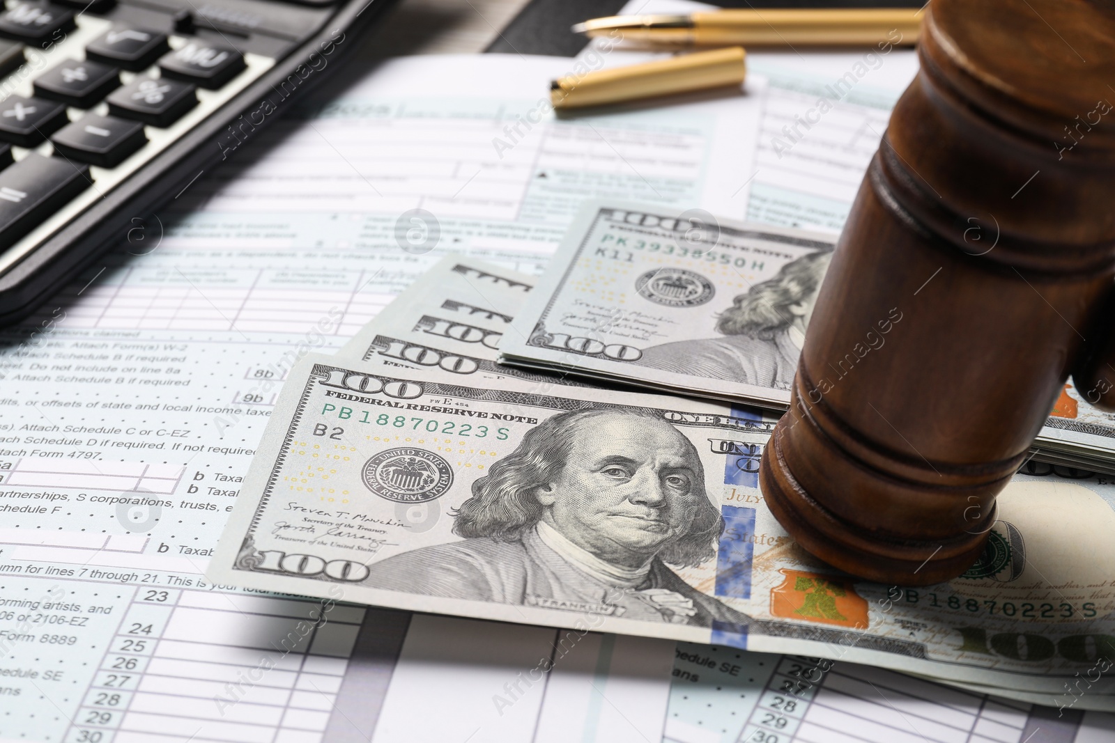 Photo of Tax return forms, dollar banknotes, gavel and calculator on table, closeup