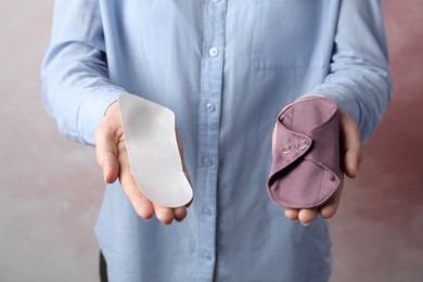 Photo of Woman holding disposable and reusable cloth menstrual pads on grey background, closeup