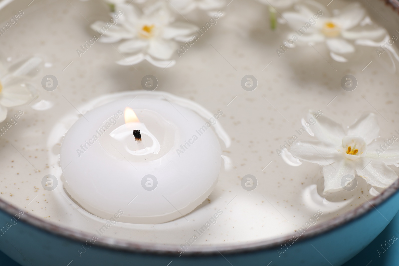 Photo of Spa composition with burning candle and beautiful flowers in water, closeup