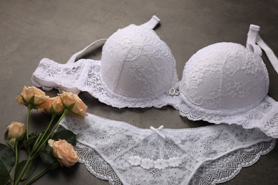 Photo of Elegant white women's underwear and beautiful roses on grey background