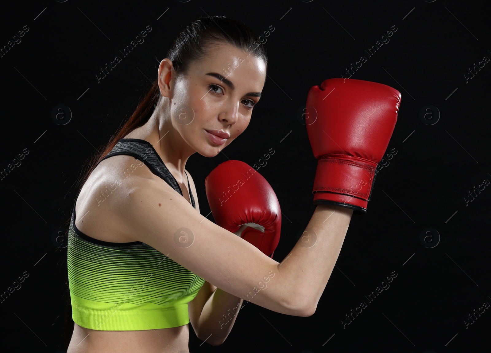 Photo of Portrait of beautiful woman in boxing gloves on black background