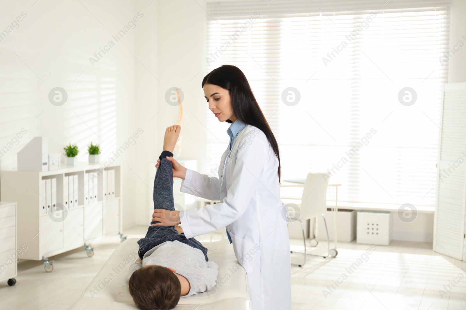 Photo of Professional orthopedist examining little patient's leg in clinic