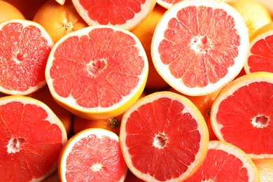 Many sliced fresh grapefruits as background, top view