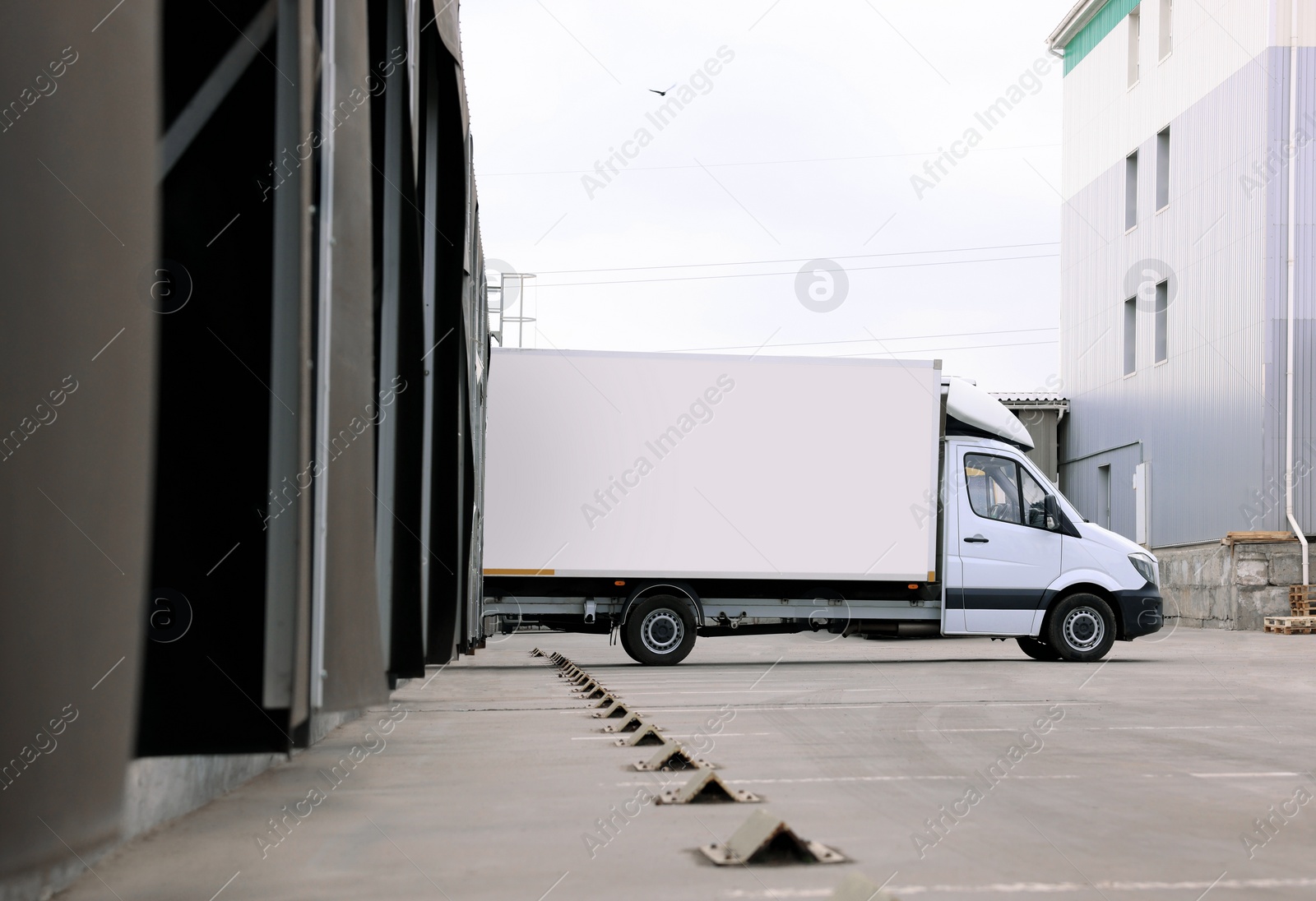 Image of Truck near loading dock of warehouse outdoors. Logistics center