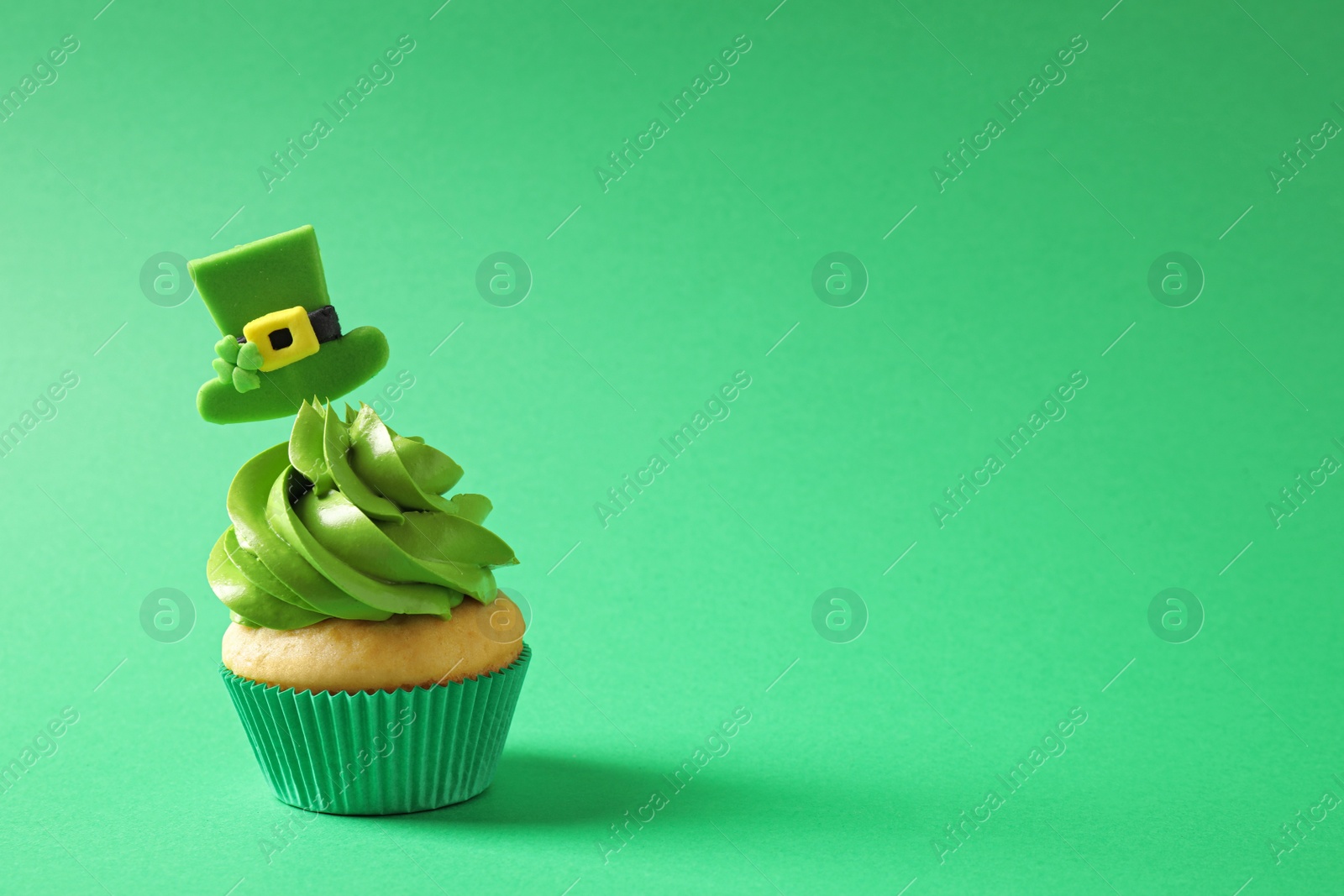 Photo of Delicious decorated cupcake on green background, space for text. St. Patrick's Day celebration