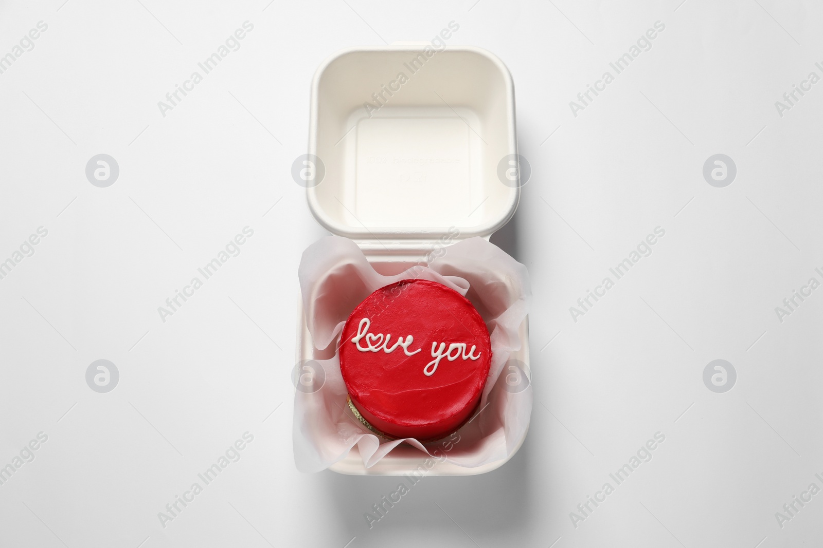 Photo of Bento cake with Love You text in takeaway box on white table, top view. St. Valentine's day surprise