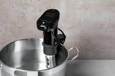 Thermal immersion circulator in pot on white table, space for text. Sous vide cooker