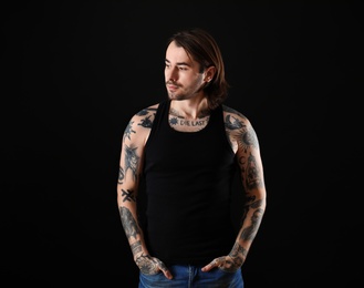 Photo of Young man with tattoos on body against black background