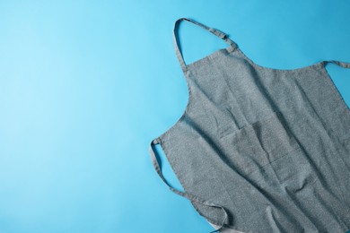 Photo of Grey apron with pattern on blue background, top view. Space for text