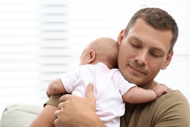 Happy father with his little baby near window