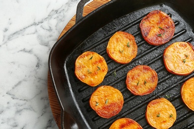 Photo of Grill pan with sweet potato fries on marble background, top view. Space for text