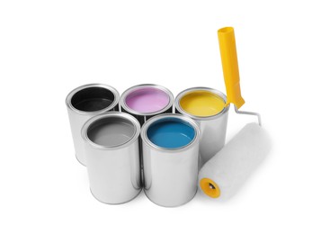 Cans of different paints with roller on white background