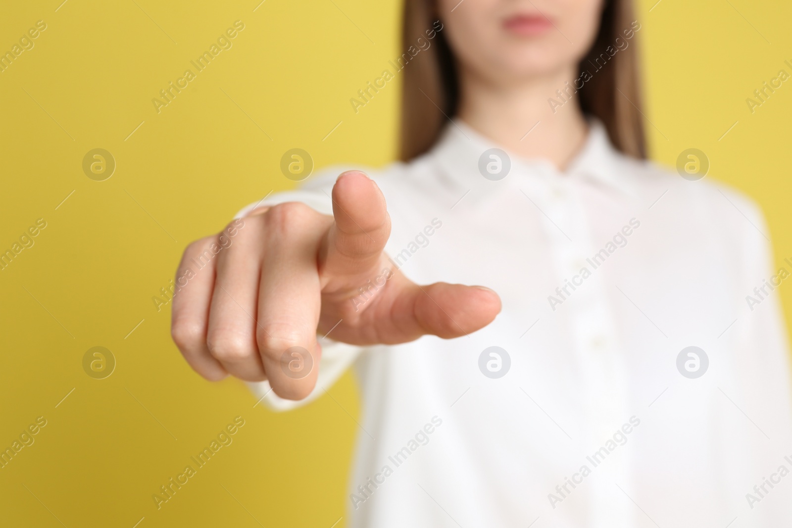 Photo of Young woman against yellow background, focus on hand