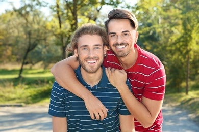 Photo of Portrait of happy gay couple smiling in park