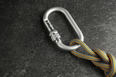 One metal carabiner with rope on black table, closeup