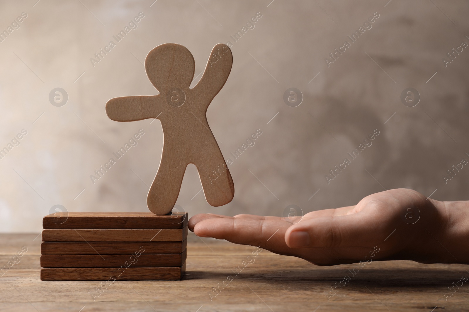 Photo of Woman holding human figure near wooden blocks at table, closeup