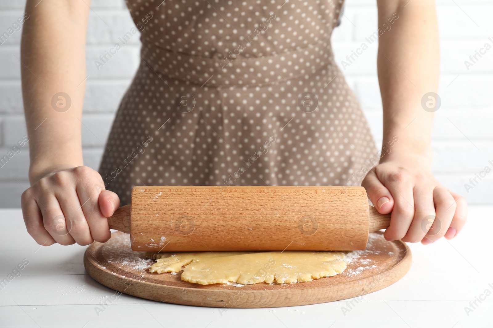 Photo of Making shortcrust pastry. Woman rolling raw dough at white wooden table, closeup