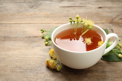 Cup of tea and linden blossom on wooden table. Space for text