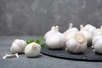 Slate plate with fresh garlic bulbs on table