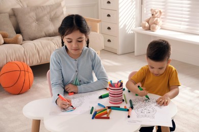 Photo of Cute children coloring drawings at table in room