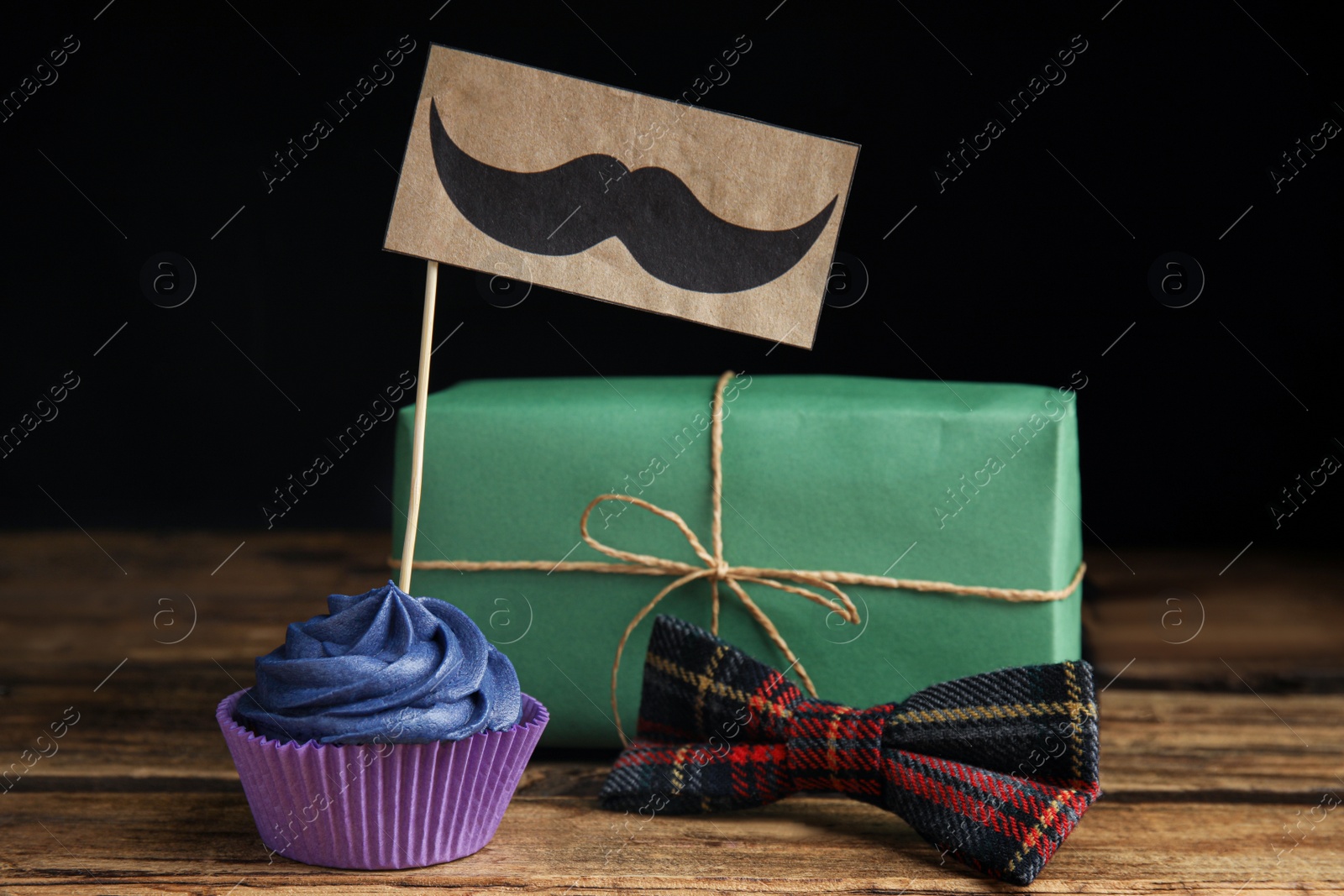 Photo of Composition with cupcake and gift box on wooden table. Happy Father's day