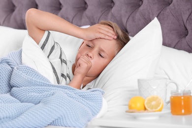 Ill boy suffering from cough in bed at home