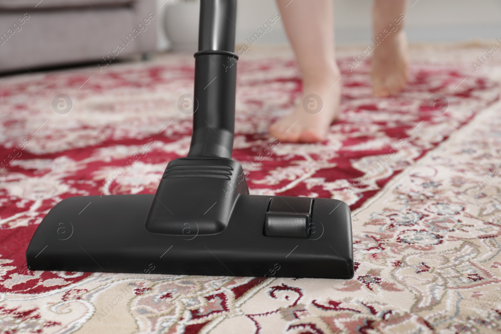 Photo of Woman cleaning carpet with vacuum cleaner at home, closeup