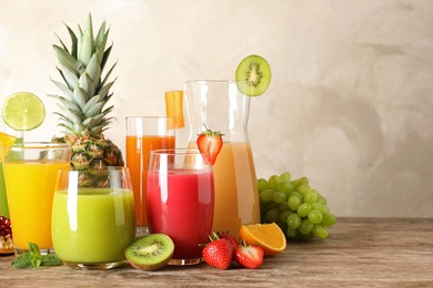 Glassware with different juices and fresh fruits on table. Space for text