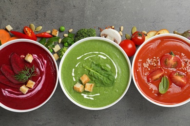 Photo of Various cream soups and ingredients on grey background, flat lay. Healthy food