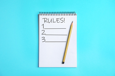 Notepad with list of rules and pencil on light blue background, top view