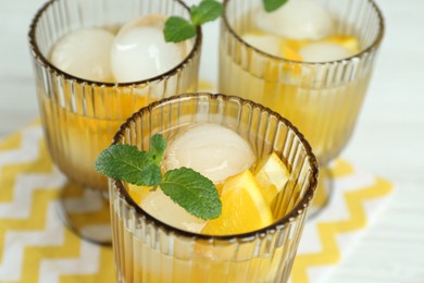 Photo of Delicious cocktails with orange, mint and ice balls on table, closeup