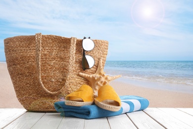 Image of Beach accessories on white wooden surface near ocean 