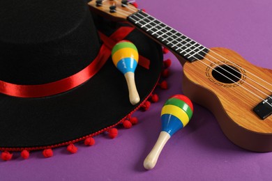 Photo of Black Flamenco hat, ukulele and maracas on purple table, closeup