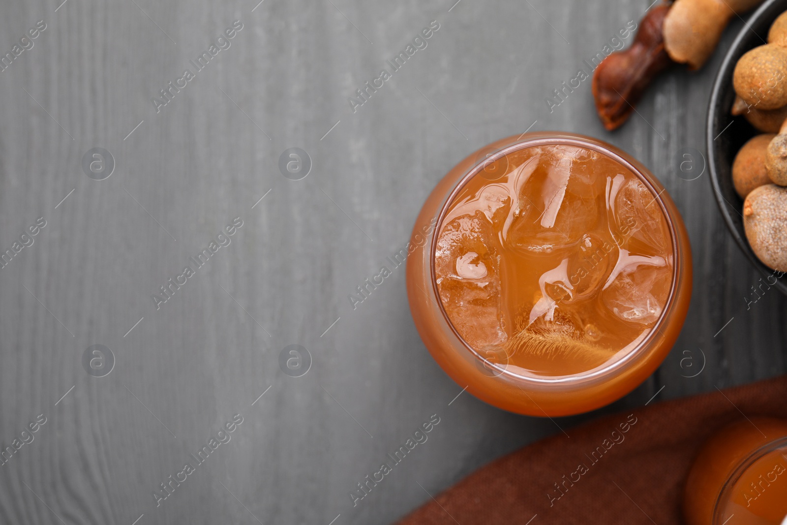 Photo of Freshly made tamarind juice on grey wooden table, flat lay. Space for text