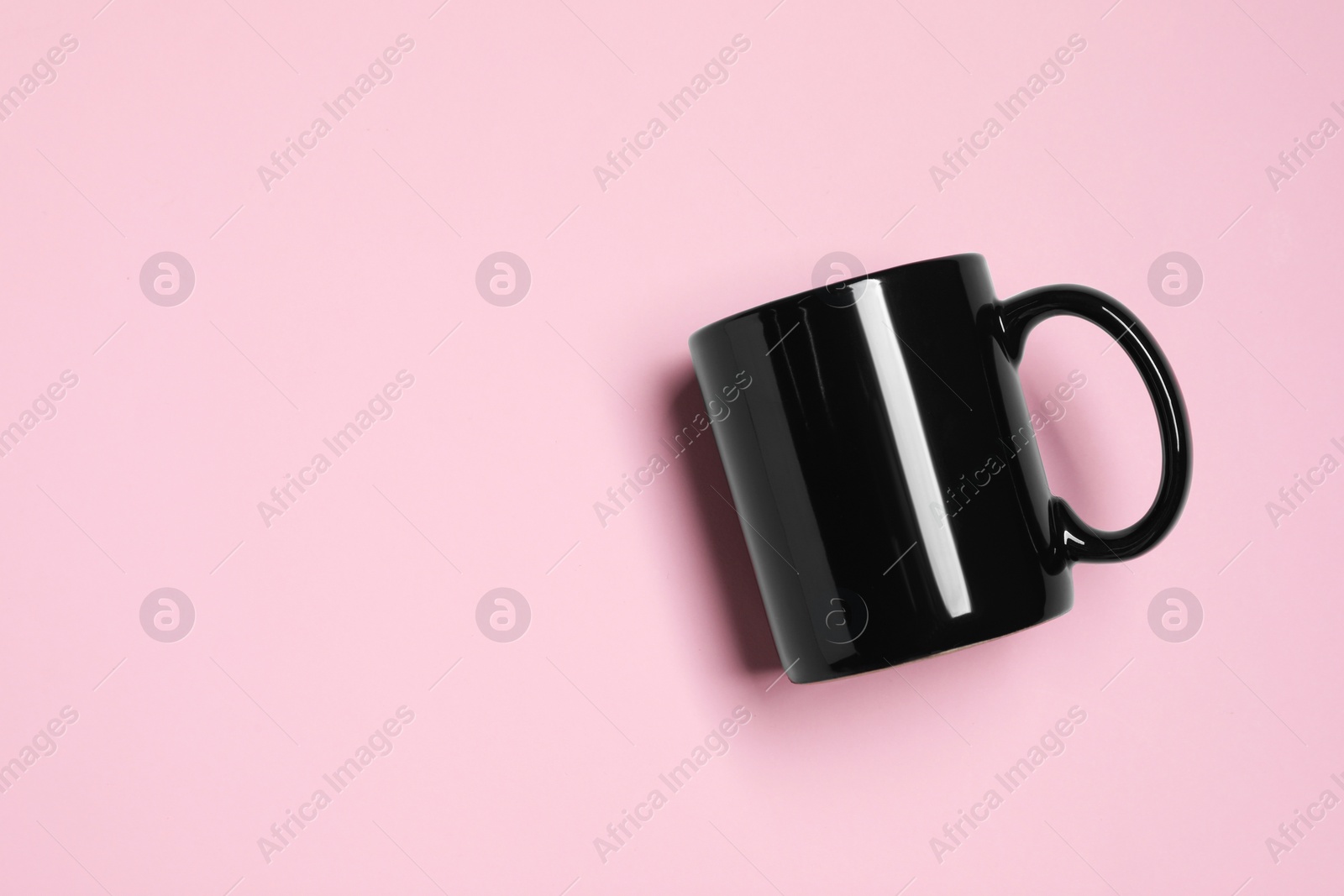 Black ceramic mug on pink background, top view. Space for text Photo of Black ceramic mug on pink background, top view. Space for text