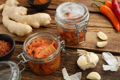 Photo of Delicious kimchi with Chinese cabbage and ingredients on wooden table, closeup
