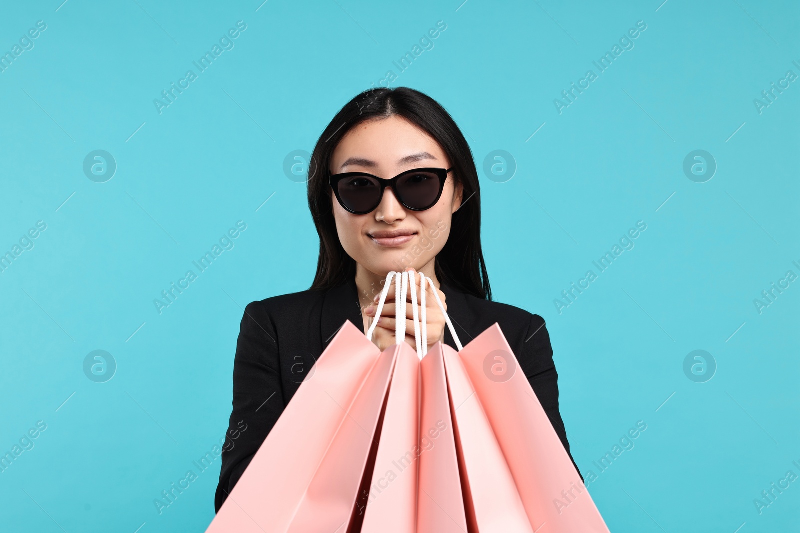 Photo of Beautiful woman with shopping bags on light blue background