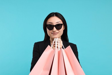 Photo of Beautiful woman with shopping bags on light blue background