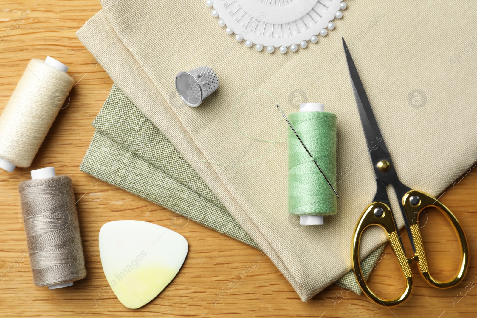 Photo of Flat lay composition with threads and sewing tools on wooden table