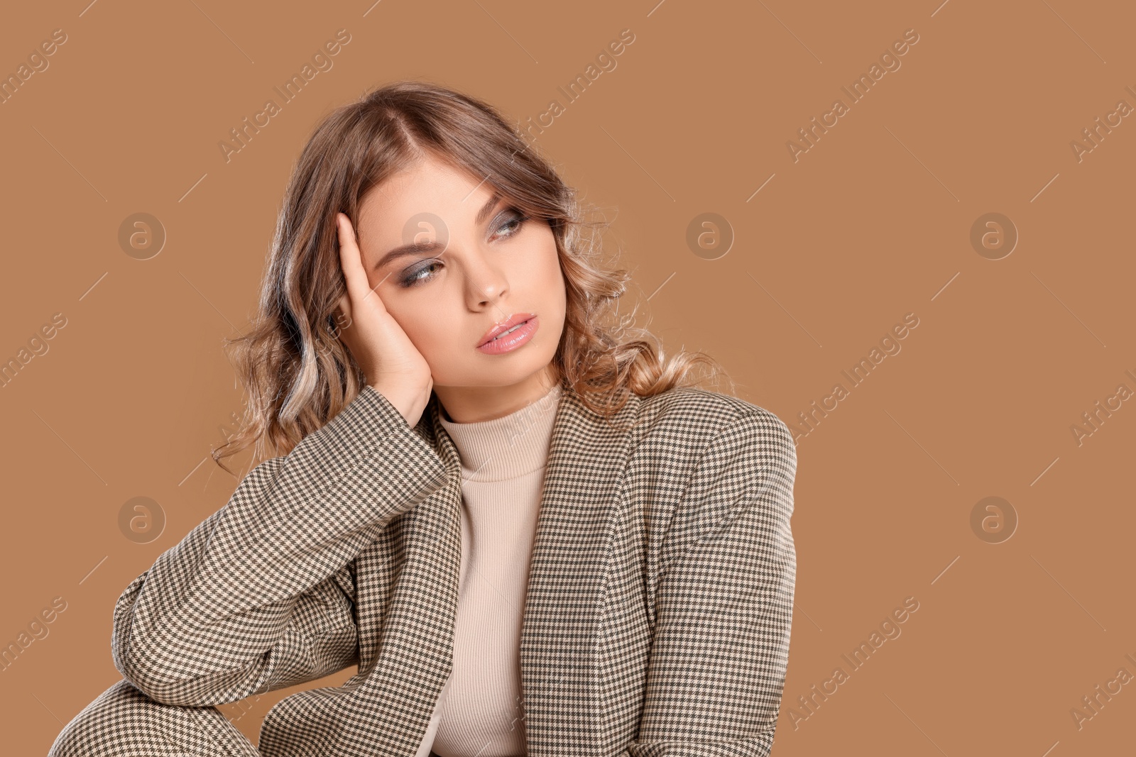 Photo of Portrait of young woman with beautiful makeup on light brown background