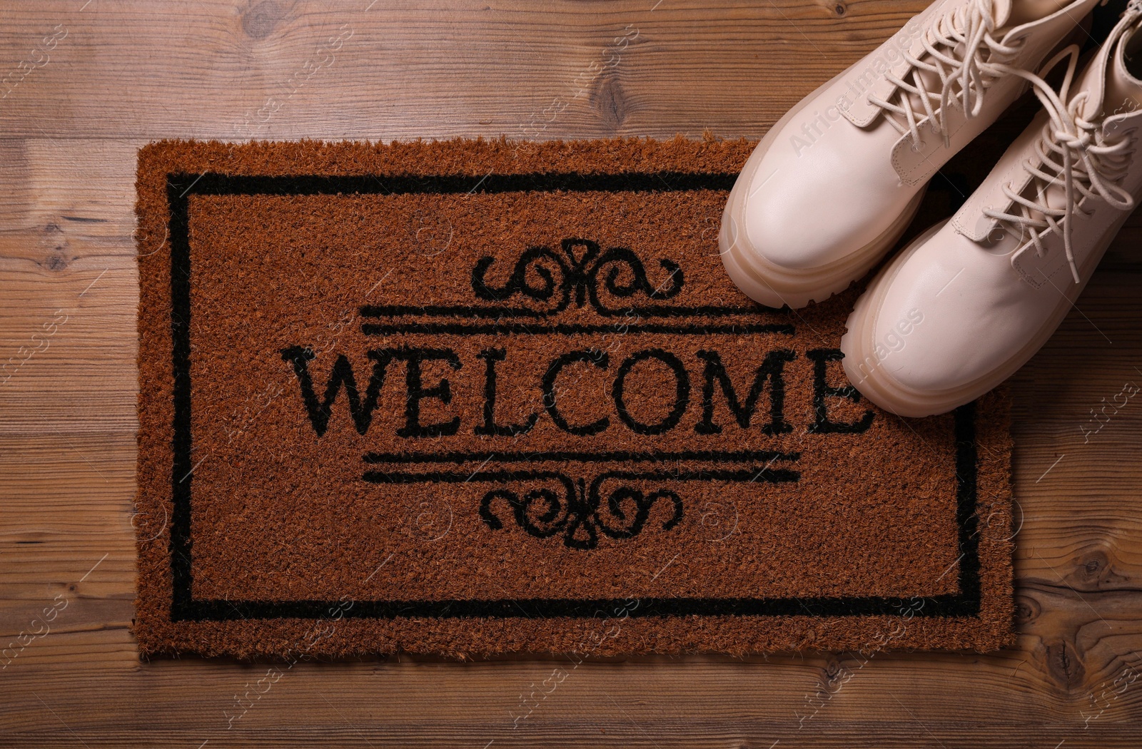 Photo of Doormat with word Welcome and stylish boots on wooden floor, flat lay