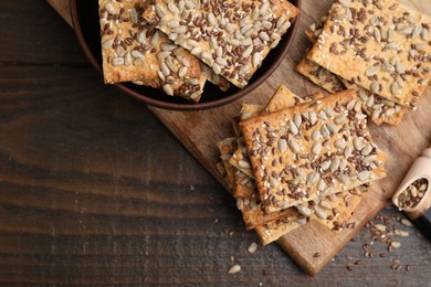 Photo of Cereal crackers with flax, sunflower and sesame seeds on wooden table, top view. Space for text