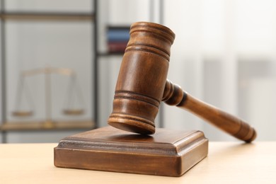 Photo of Wooden gavel and sound block on table indoors, closeup